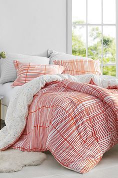 an orange and white comforter set on a bed