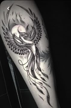 a black and white photo of a woman's leg with a bird tattoo on it