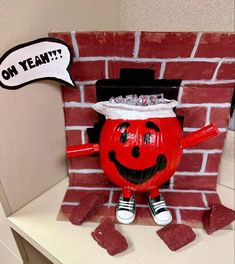 a red pumpkin with a hat on its head and hands in front of a brick wall