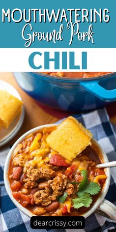 a white bowl filled with chili and topped with tortilla chips next to a blue casserole dish