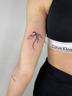 a woman's arm with a small dragon tattoo on the left side of her right arm