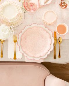 the table is set with pink and white plates, silverware, and napkins