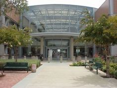 the entrance to an office building with lots of trees and benches in front of it