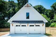 a white house with two garages and a black roof