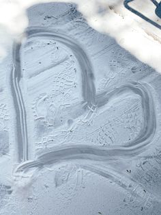 a heart drawn in the snow on a sidewalk