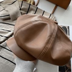 a woman's brown hat on top of a white table next to a purse