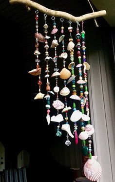 a wind chime hanging from a tree branch with seashells and shells on it