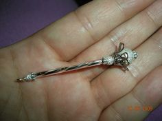 a small silver brooch with a bow on it's end in someones hand