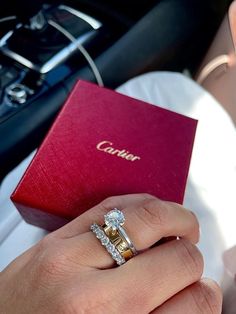 a woman's hand holding an engagement ring in front of a red box with the word canon on it