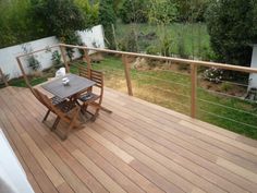 a wooden deck with table and chairs next to a fenced in area that looks out onto the yard