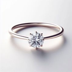 an engagement ring with a single diamond in the center on a white surface, close up