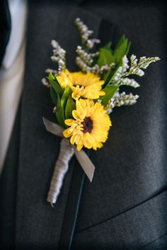 a boutonniere with yellow flowers and greenery on it's lapel