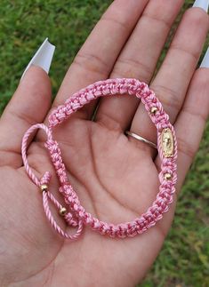 a hand holding a pink bracelet with gold beads