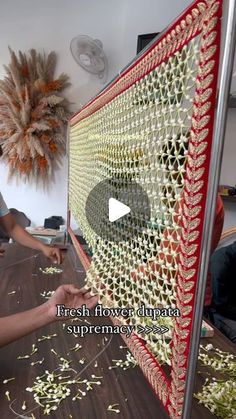 a woman is working on a piece of art with yarn and beads in front of her