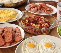 a table topped with plates of food and bowls of eggs, sausages, hash browns