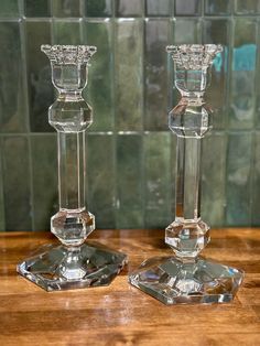 two crystal candlesticks sitting on top of a wooden table