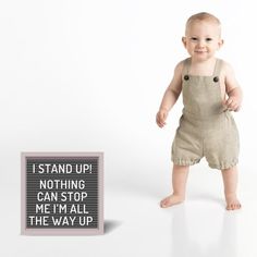 a baby standing next to a sign that says i stand up nothing can stop me i'm all the way up