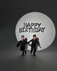 two small children standing in front of a happy birthday sign