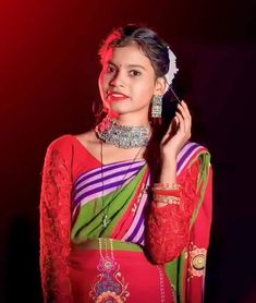 a woman in a red and green sari is talking on her cell phone while wearing jewelry