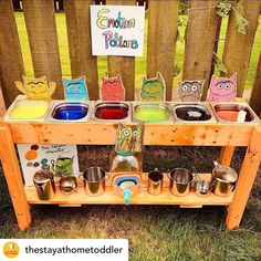 a wooden table with bowls and cups on it in front of an outdoor play area