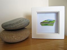 two rocks are stacked on top of each other in front of a small white frame