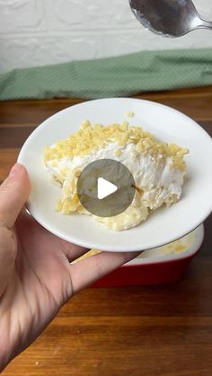 a person holding a white plate with food on it and a spoon in the background