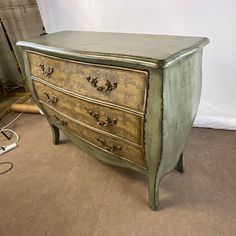 an old green dresser sitting on top of a carpeted floor