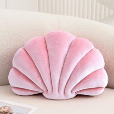 a pink shell shaped pillow sitting on top of a couch