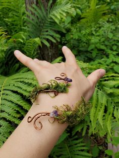 Step into a world of enchantment and healing with this whimsical fairy-inspired jewelry set. Handcrafted with love and meticulous attention to detail, our copper woven bracelet adorned with amethyst and moss is the perfect accessory for anyone seeking a touch of magic in their lives. Complementing the bracelet, our charming pinecone earrings with moss add a delightful, natural touch to your ensemble. Note: Made for 3" wide wrist **Healing Properties - **Copper Known for its healing properties, c