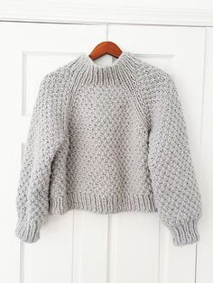 a gray sweater hanging on a white door