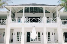 a large white house with palm trees in the background