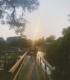 two people walking across a wooden bridge over water