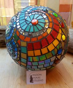 a multicolored glass ball sitting on top of a wooden table next to a sign