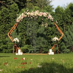 an outdoor wedding ceremony setup with flowers and greenery on the grass, surrounded by tall trees