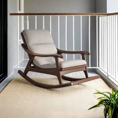 a rocking chair sitting on top of a carpeted floor next to a plant in a vase