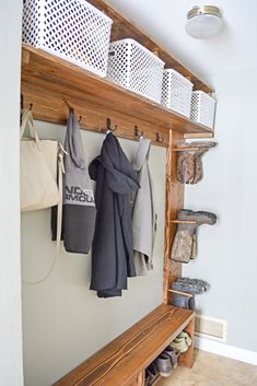 a coat rack with several coats hanging from it's hooks and baskets on the wall