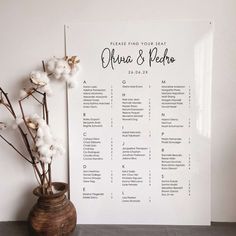 a wedding seating chart with cotton flowers in a vase