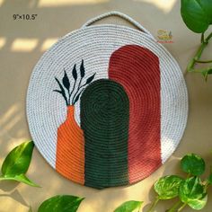 a woven basket with two carrots painted on it and some green plants in the background