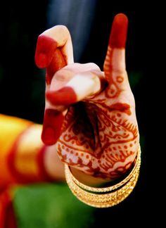 a woman's hand with hendi and bracelets on it making the peace sign