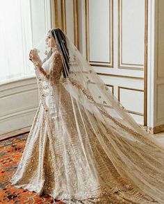 a woman in a wedding dress with a veil on her head is looking down at the floor