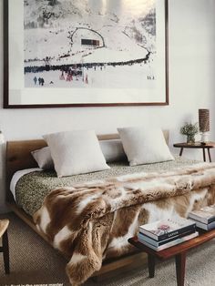 a bedroom with a bed covered in fur and white pillows next to a painting on the wall