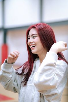 a woman with red hair is smiling and raising her arms