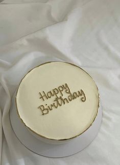 a birthday cake with the words happy birthday written on it, sitting on a white cloth