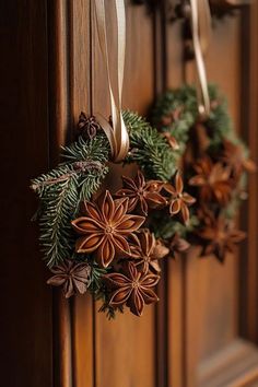 two christmas wreaths hanging on a door with ribbons and pine cones attached to them