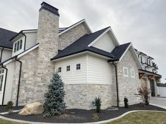 a house with stone and black shingles on the roof