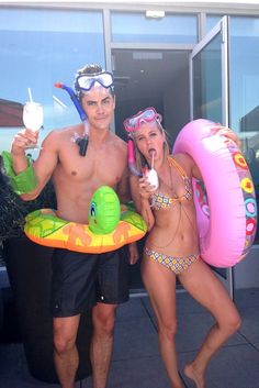 two people in swimsuits standing next to each other with floaties on their heads