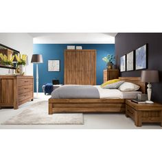 a bed room with a neatly made bed and wooden furniture on the floor next to a blue wall