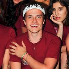 a group of young people sitting next to each other in front of a man wearing a bandana