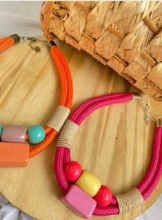 two colorful necklaces on a wooden tray next to a straw hat with beads in it