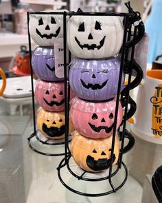 halloween pumpkin mugs with faces on them are stacked up in a display rack at a store